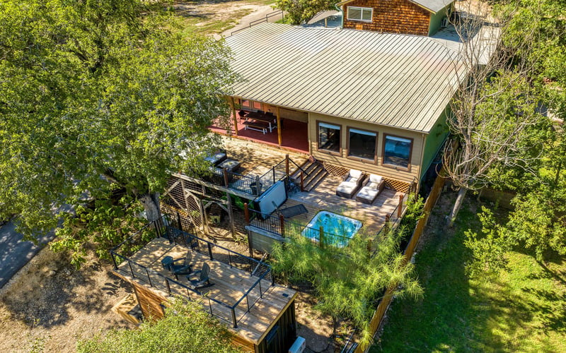 New Braunfels Vacation rental with a spacious deck, outdoor lounge seating, a hot tub, and a private rooftop patio, surrounded by lush greenery.